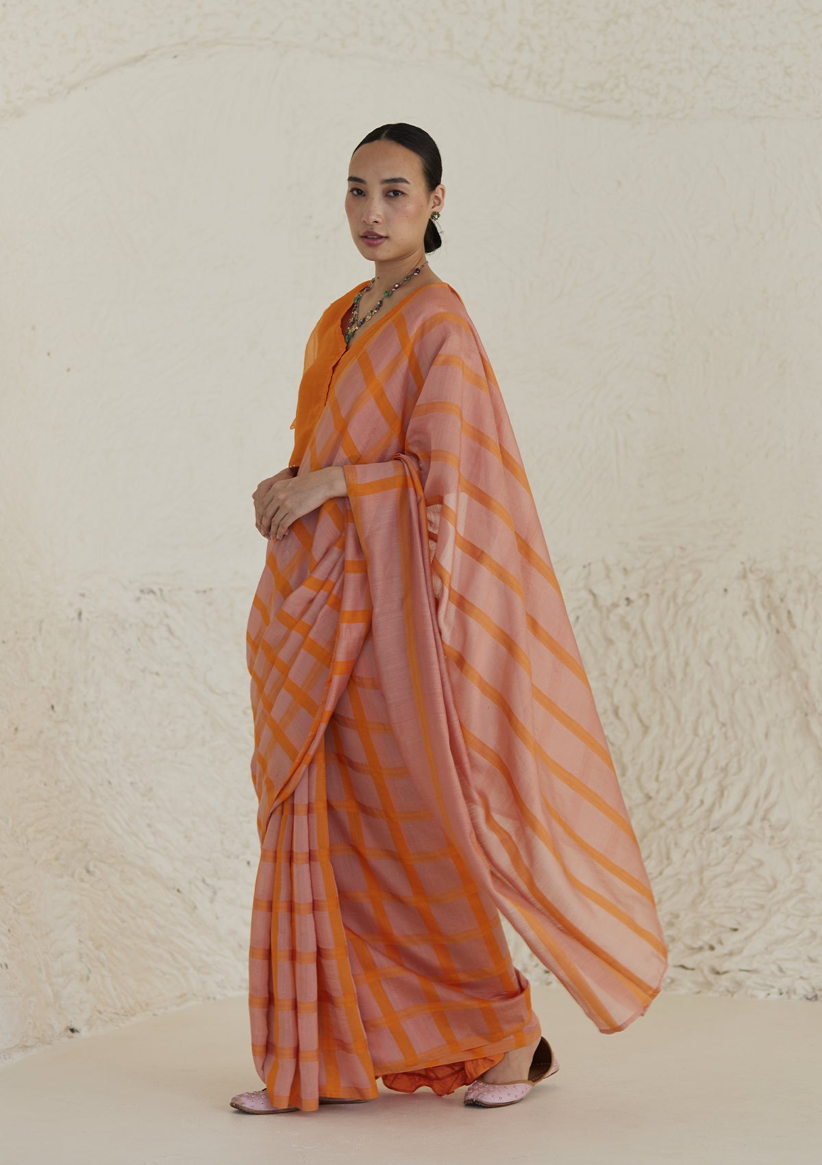 Handloom silk modal saree from Surmaye, having a check pattern with shades of pink and orange.
