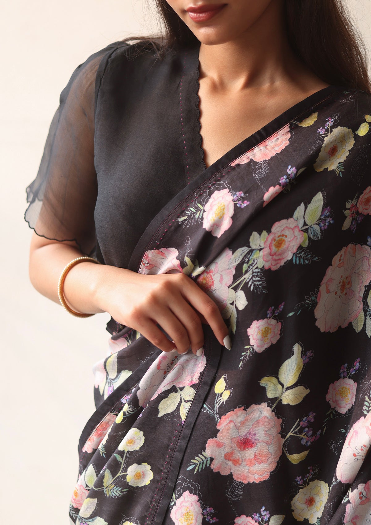 Black designer blouse, crafted in handwoven organza silk, from Surmaye. Scalloped embroidery edges all over. Lined with handwoven mulberry silk. Paired with Harmony Black floral saree.