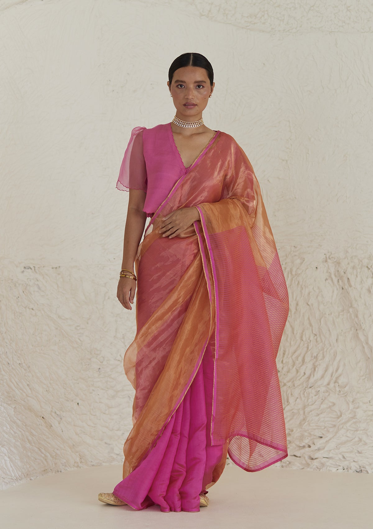 Handloom silk saree in dual colour, from Surmaye. Pink organza mulberry silk panel till pleats, followed by orange silk zari panel and pink stripes at the pallu edge.