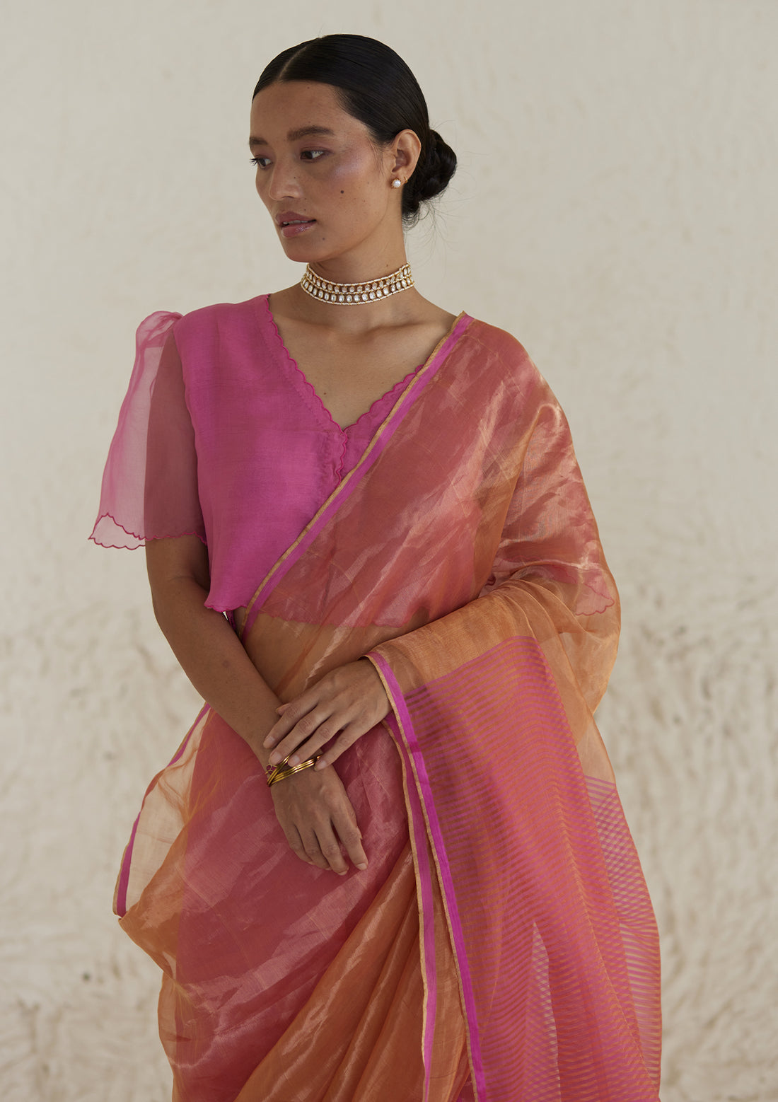 Handloom silk saree in dual colour, from Surmaye. Pink organza mulberry silk panel till pleats, followed by orange silk zari panel and pink stripes at the pallu edge.