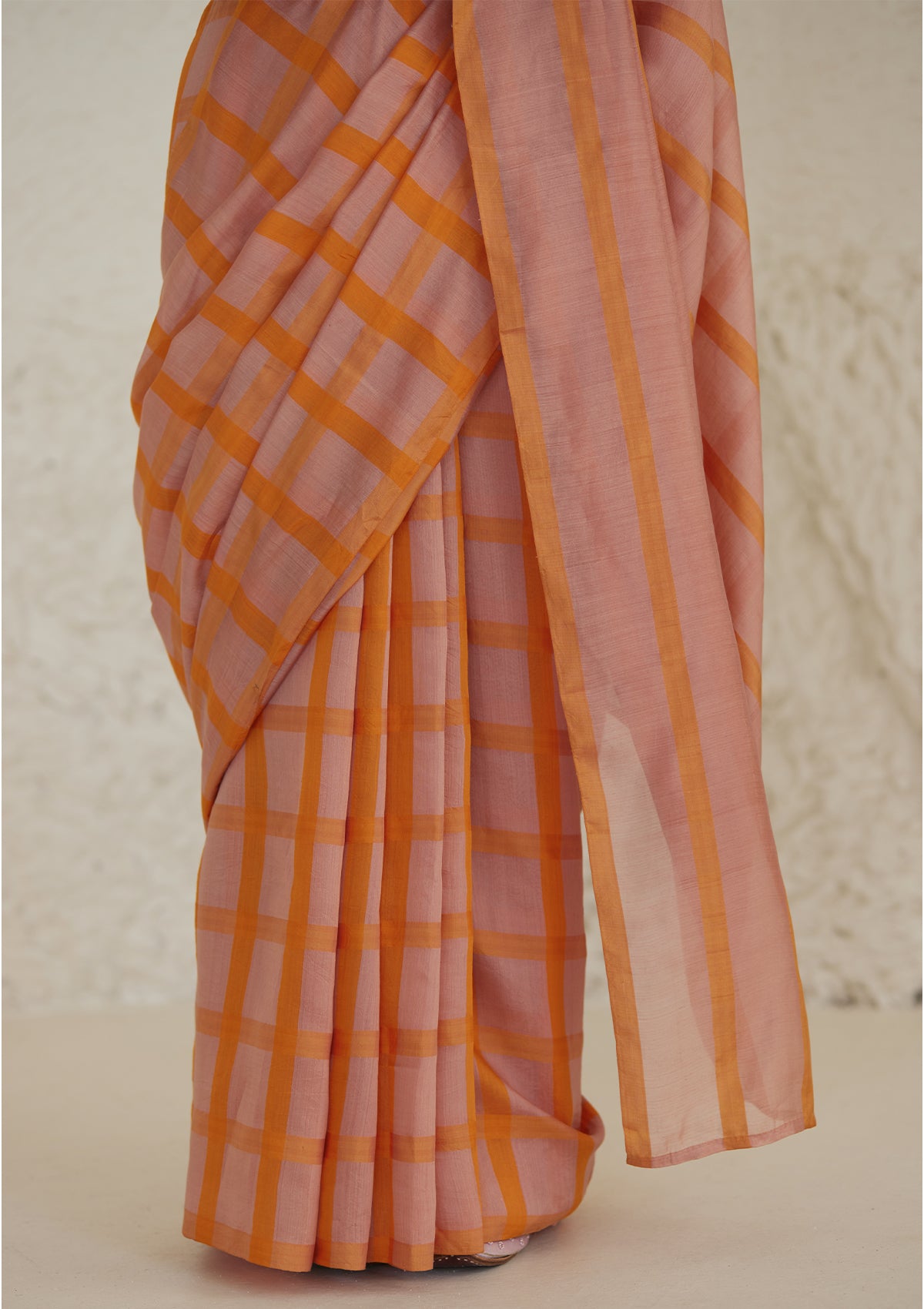 Handloom silk modal saree from Surmaye, having a check pattern with shades of pink and orange. Close-up.