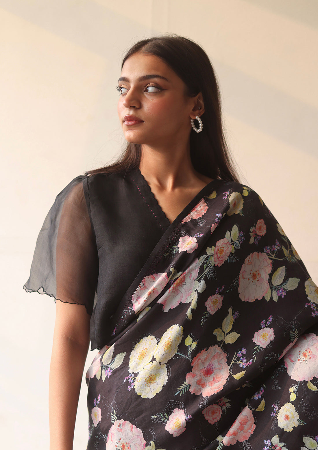 Black designer blouse, crafted in handwoven organza silk, from Surmaye. Scalloped embroidery edges all over. Lined with handwoven mulberry silk. Paired with Harmony Black floral saree.