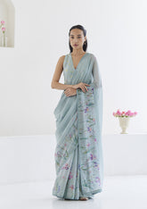 Handloom organza mulberry silk saree in seafoam, from Surmaye. Intricate, hand-drawn, iris flower border print. Paired with seafoam designer blouse in floral print.