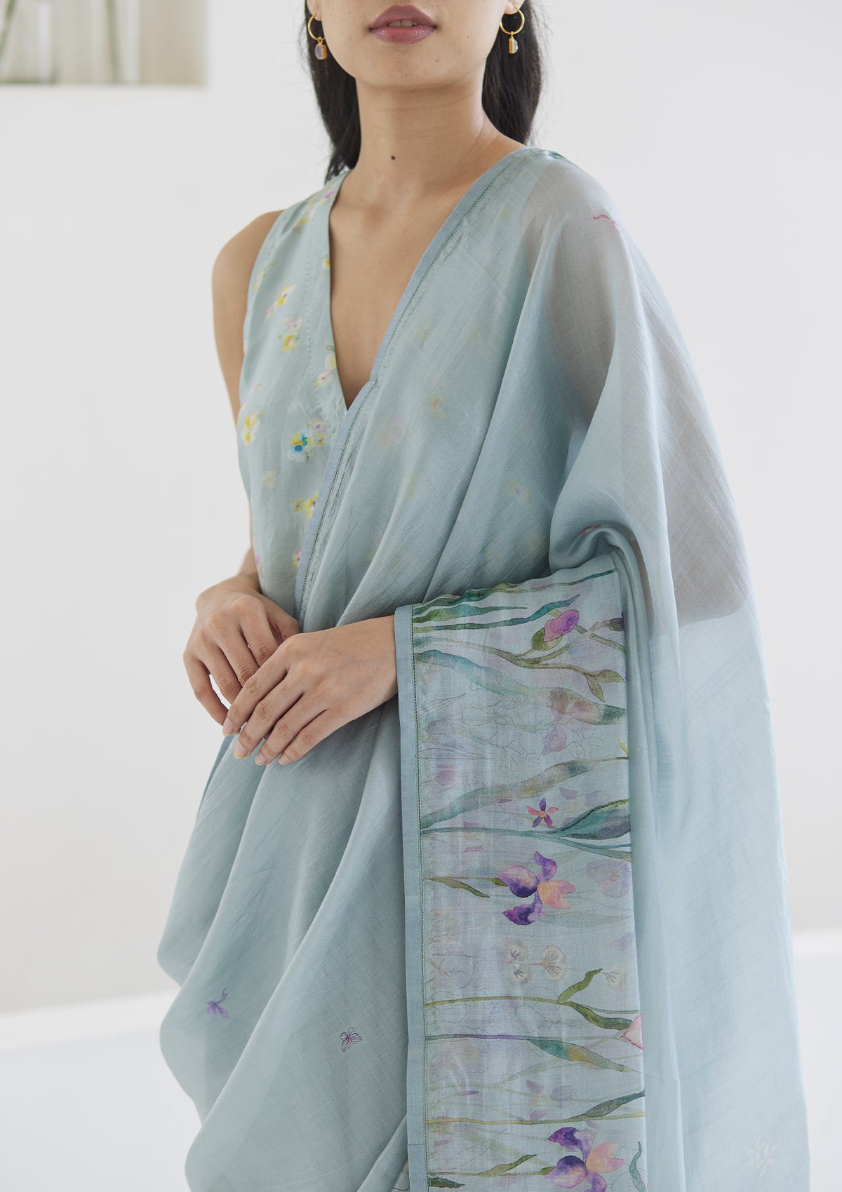 Handloom organza mulberry silk saree in seafoam, from Surmaye. Intricate, hand-drawn, iris flower border print. Paired with seafoam designer blouse in floral print.