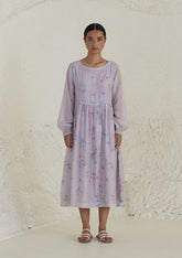 Floral mauve dress in silk modal, from Surmaye. All-over pansy print, handmade in watercolour. Round neckline, and a full sleeve ruched at the hem.