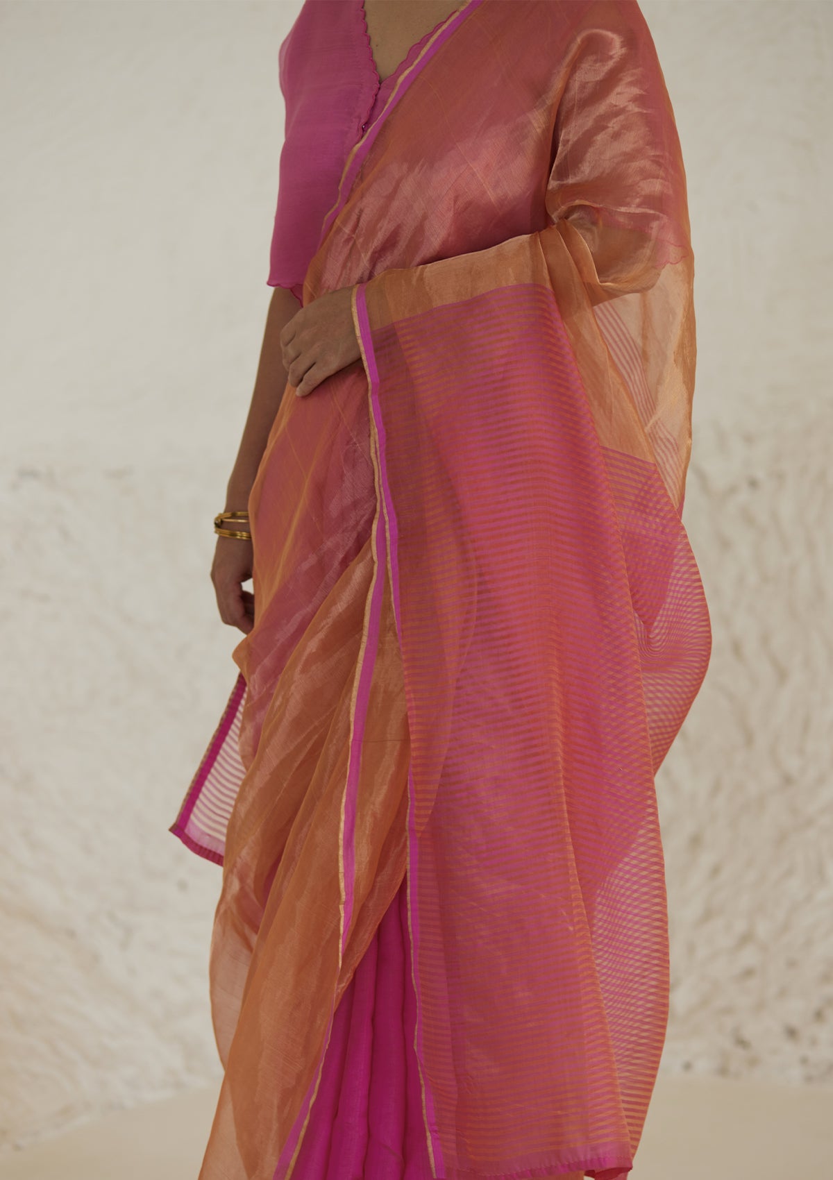 Handloom silk saree in dual colour, from Surmaye. Pink organza mulberry silk panel till pleats, followed by orange silk zari panel and pink stripes at the pallu edge. 