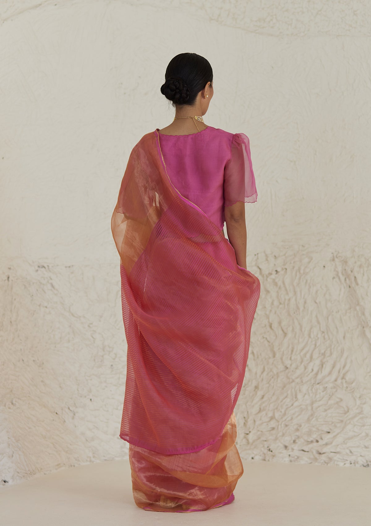 Handloom silk saree in dual colour, from Surmaye. Pink organza mulberry silk panel till pleats, followed by orange silk zari panel and pink stripes at the pallu edge. 