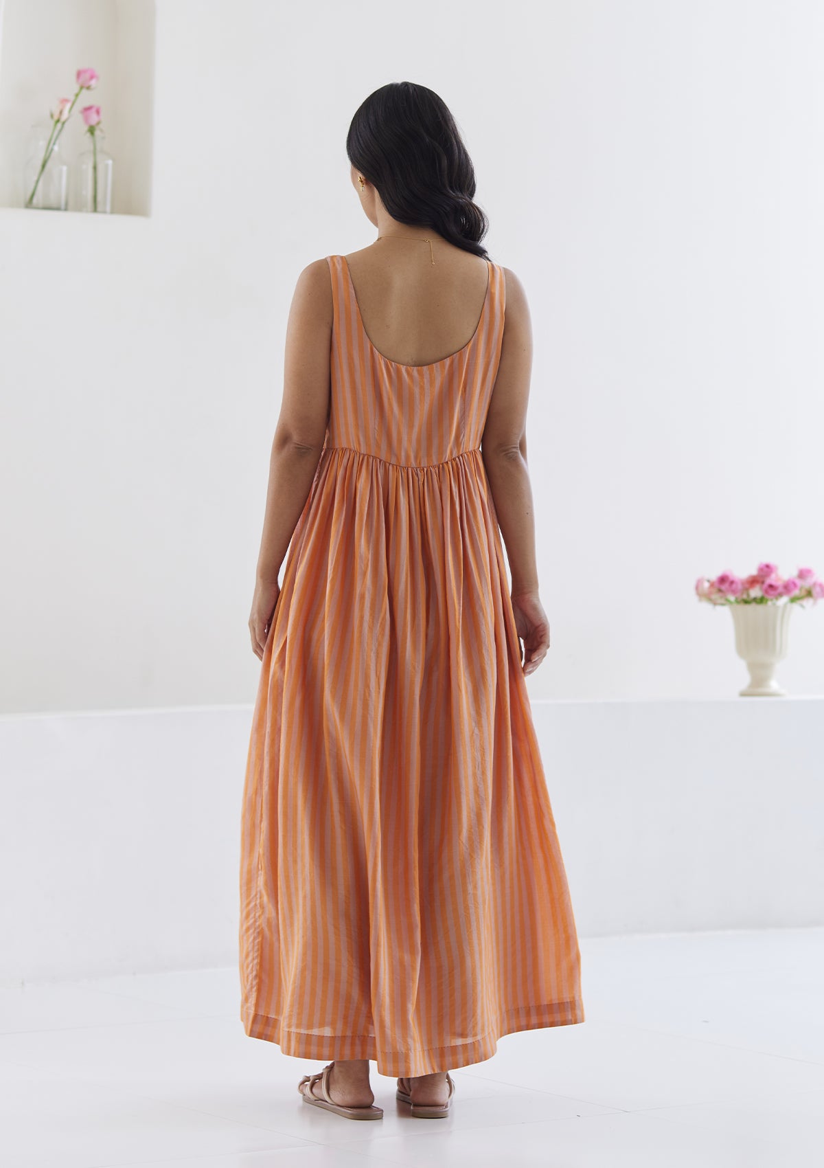 Handwoven maxi dress in silk modal, from Surmaye. Sleeveless dress in a fit-and-flare silhouette, with pink and orange stripes. Back view.