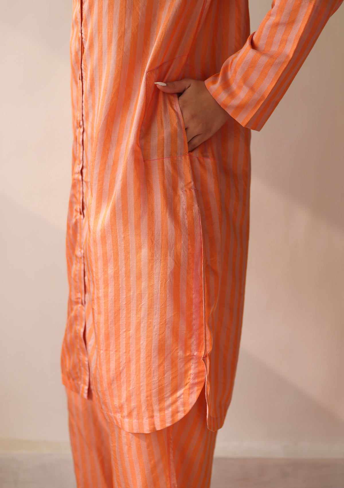 Kurta set for women, in orange stripes, from Surmaye. Made in handwoven silk modal with a relaxed silhouette. Vibrant contrast-pink checked fabric detailing.