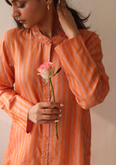 Kurta set for women, in orange stripes, from Surmaye. Made in handwoven silk modal with a relaxed silhouette. Vibrant contrast-pink checked fabric detailing.