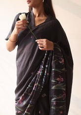 Handloom organza mulberry silk saree in black, from Surmaye. Intricate, hand-drawn, iris flower border print. Paired with black collar blouse.