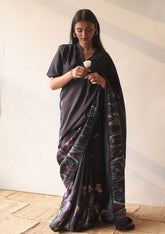 Handloom organza mulberry silk saree in black, from Surmaye. Intricate, hand-drawn, iris flower border print. Paired with black collar blouse.