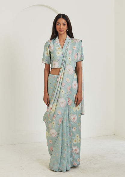 Handloom sage green saree from Surmaye. Hand-painted floral print on handwoven mulberry silk. Paired with sage green designer blouse in floral print. Full view